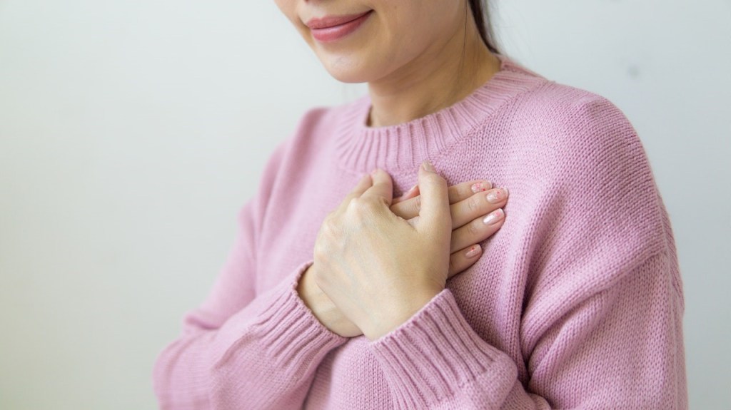 Woman holding healing hands over her heart
