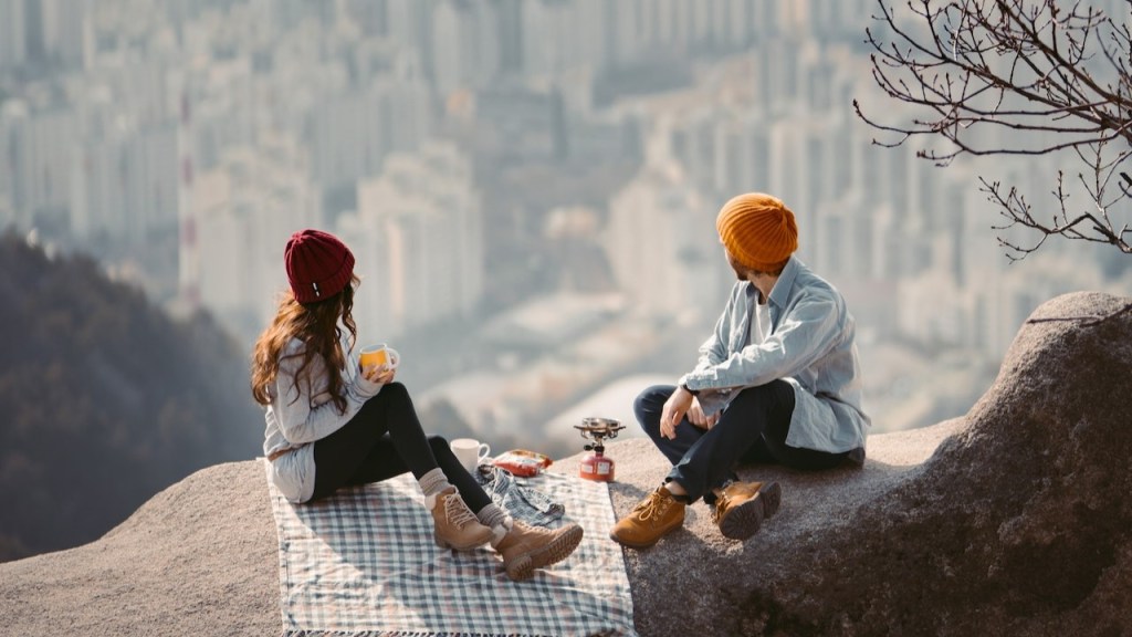 Traveling couple overlooking a city and eating a healthy picnic