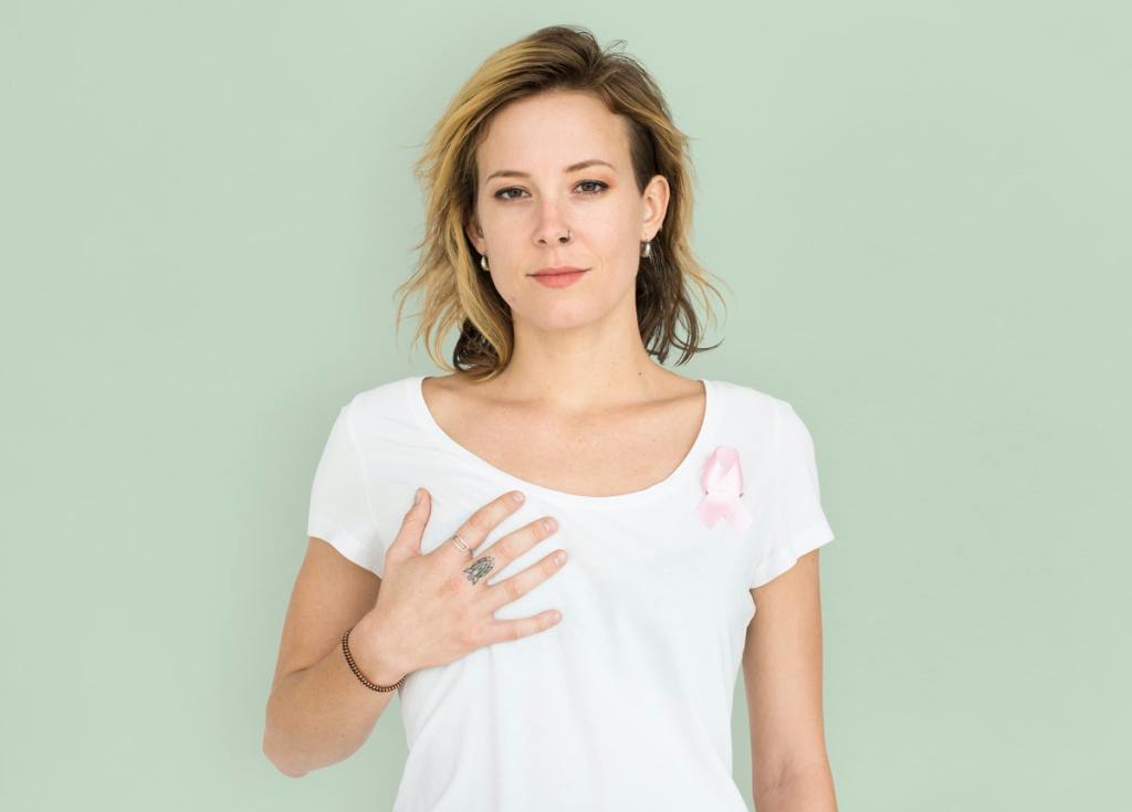 Woman with breast cancer ribbon with hand over her breast