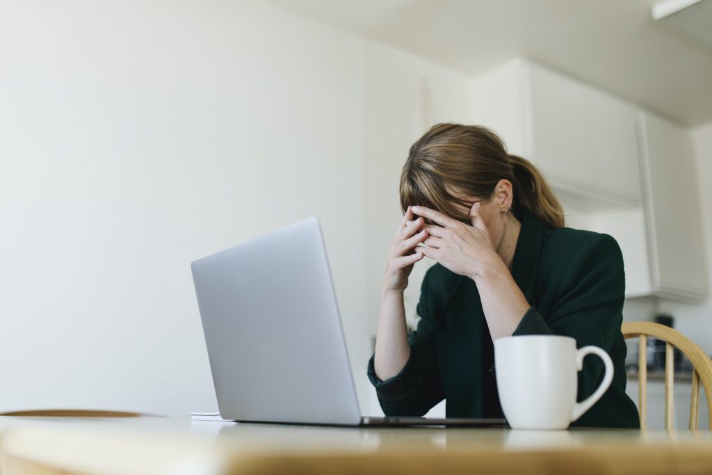 Woman sitting at a computer with hand over her eyes