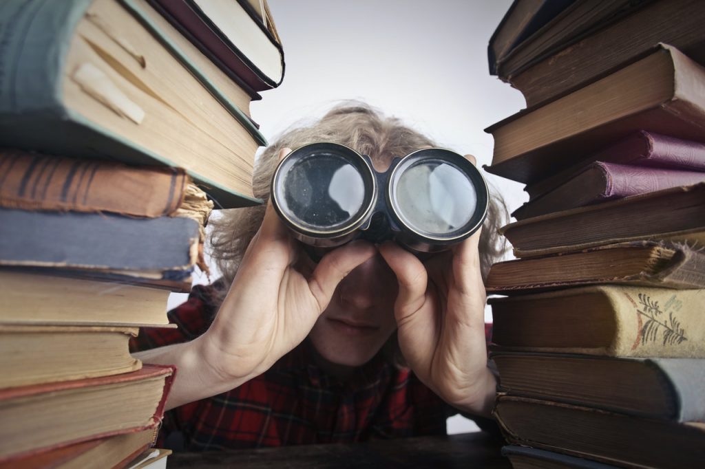 Person looking through books and binoculars