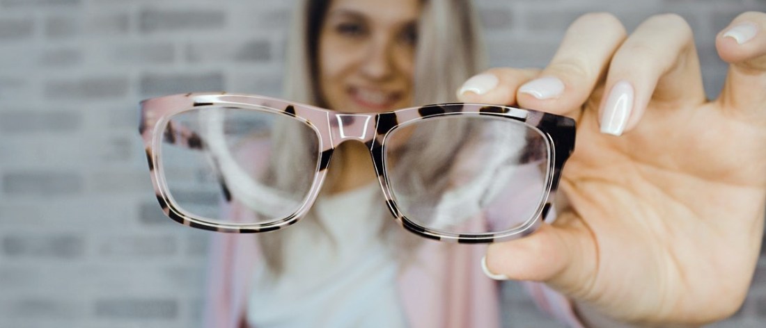 Woman holding eyeglasses - what they say about you