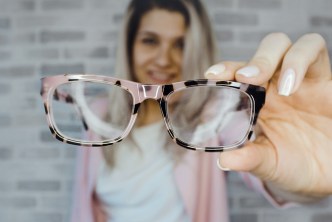 Woman holding eyeglasses - what they say about you