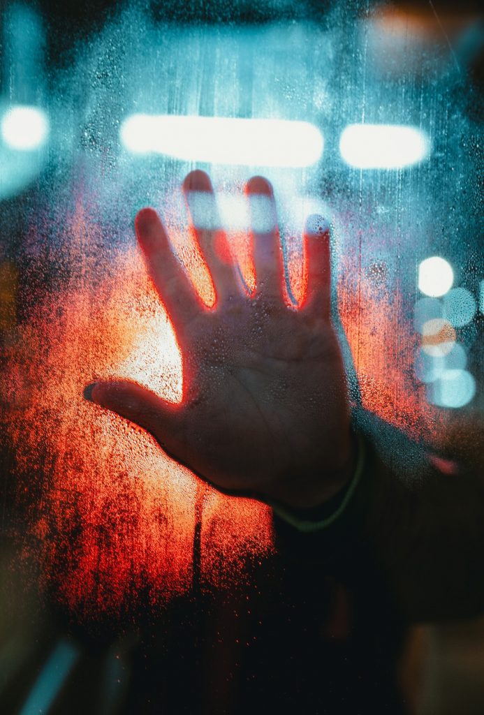 Dark hand on glass with lights in background - Face fear