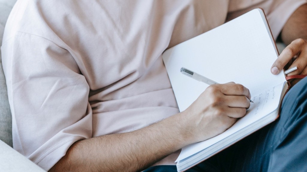 Man writing in a journal practicing self-care