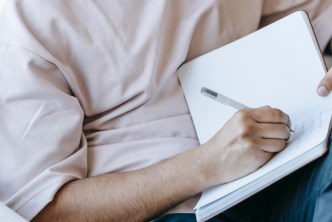 Man writing in a journal practicing self-care