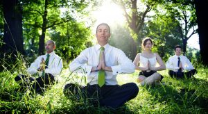 A group of of 4 people meditating in the forest in their business clothes