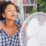 Woman having a hot flash in front of a fan