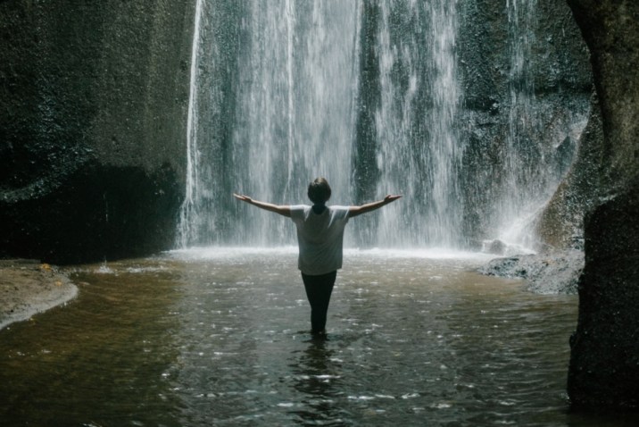 Woman in front of waterfall experiencing awakening